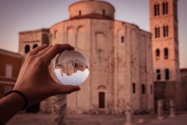 Foto pessoa segurando bola de foto pelo edifício contra o céu