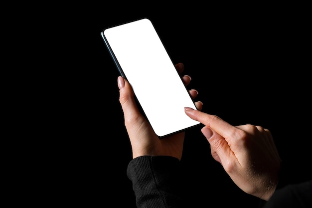 Pessoa segurando nas mãos e usando o celular com foto de tela branca vazia, isolada em preto
