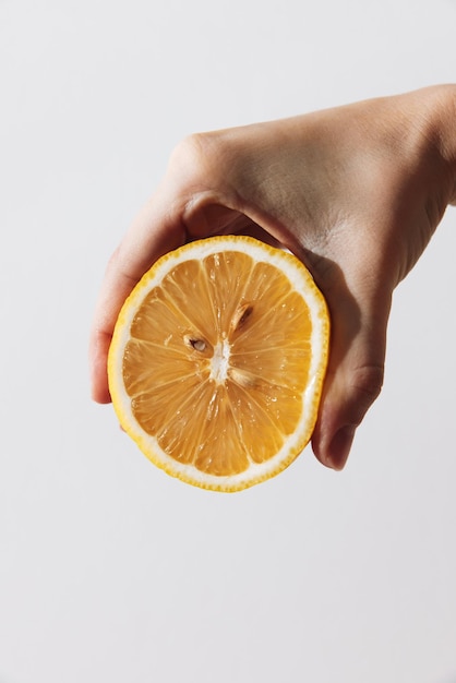Pessoa segurando uma fatia de fruta de laranja na mão em fundo branco