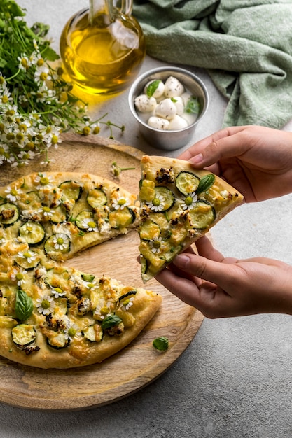 Pessoa segurando uma fatia de pizza com flores de camomila