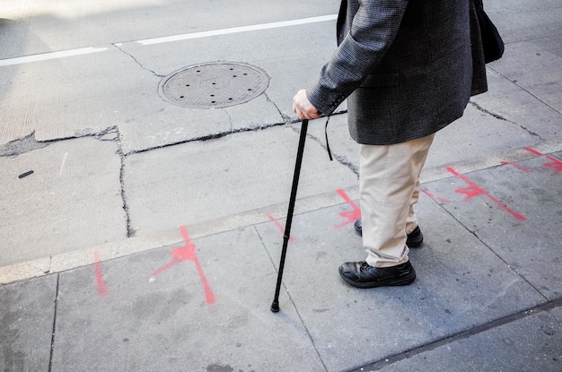 Foto pessoa solteira atravessando a rua usando uma bengala em nova york