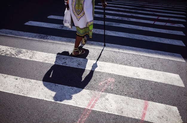 Foto pessoa solteira atravessando a rua zebra enquanto usa uma bengala de caminhada na cidade de nova york