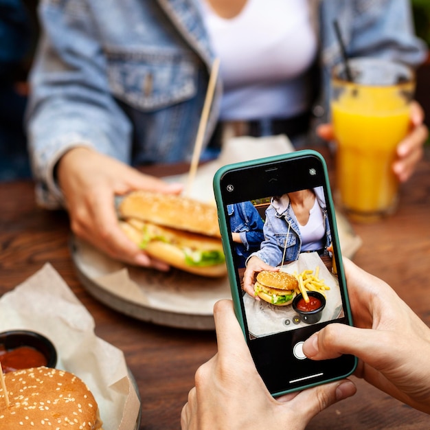 Foto pessoa tirando foto de alguém comendo hambúrguer