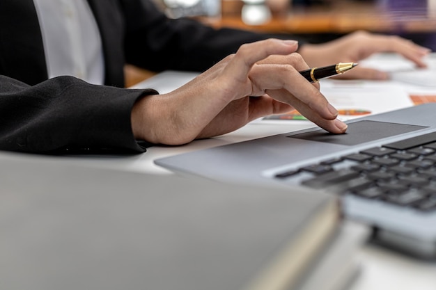 Pessoa usando laptop, mulher de negócios usando o touchpad no laptop para encontrar documentos financeiros resumidos antes da reunião com o parceiro de negócios. conceito de gestão financeira.