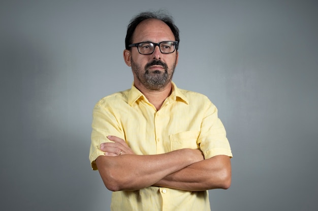 Pessoa vestida com camisa amarela com braços cruzados em fundo neutro