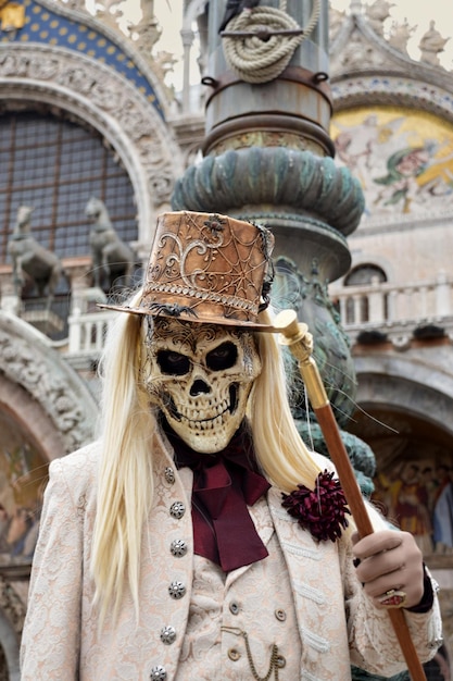 Pessoa vestida para o Carnaval de Veneza usando máscara de caveira e terno branco