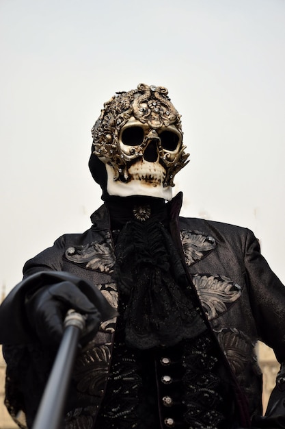 Pessoa vestida para o Carnaval de Veneza usando máscara de caveira e terno preto