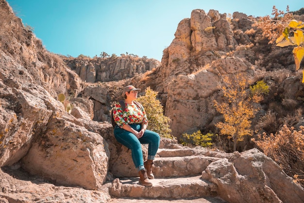 Pessoa viajante tomando um segundo fôlego sentado em alguns degraus de pedra em uma paisagem montanhosa