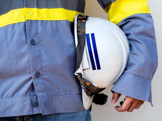 Foto pessoal da engenharia vestindo jaqueta de segurança amarela de alta visibilidade segurando um capacete de segurança branco