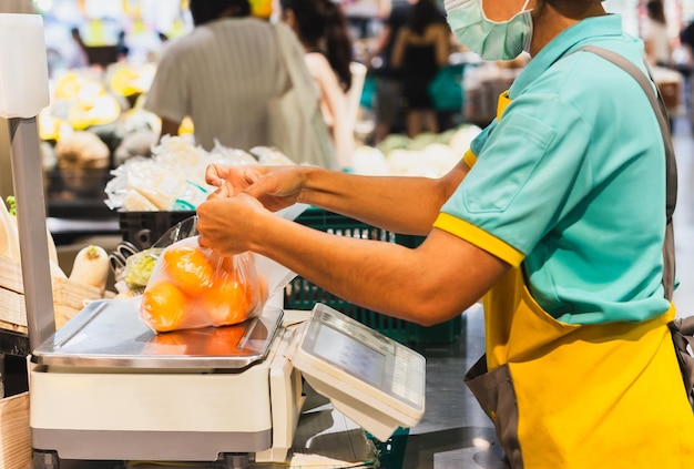 Pessoal da mercearia pesando laranjas em plástico