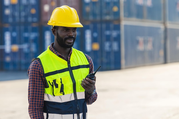 Pessoal de capataz de trabalhador africano negro trabalhando controle de carga de carga com rádio no transporte portuário