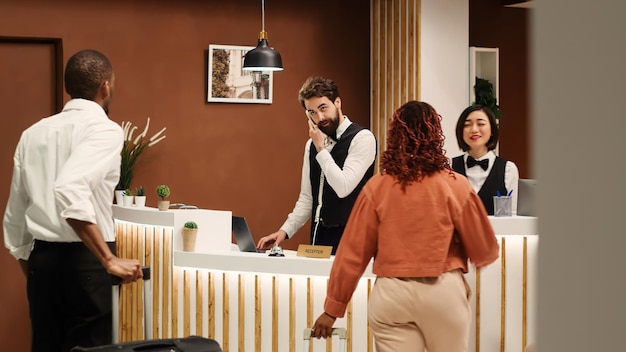 Pessoal de concierge profissional recebendo turistas na recepção durante o processo de check-in Equipe de recepcionistas elegante e amigável cumprimentando os hóspedes da viagem de férias no lobby do hotel