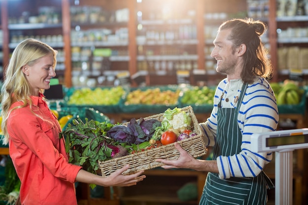 Pessoal masculino, dando uma caixa de legumes frescos para mulher na seção orgânica