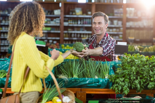 Pessoal masculino sorridente, ajudando uma mulher com compras de supermercado