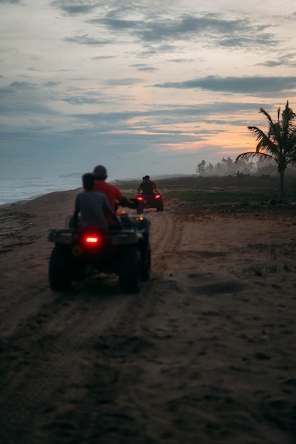 Foto pessoas a andar de quadriciclos na areia da praia