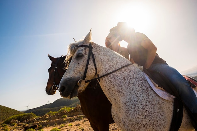 Pessoas a beijar-se sentadas em cavalos contra o céu.