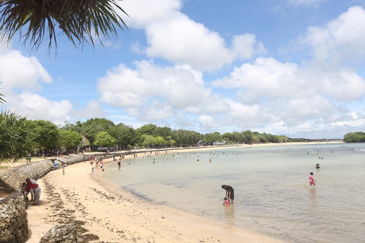 Foto pessoas a brincar na praia contra o céu nublado