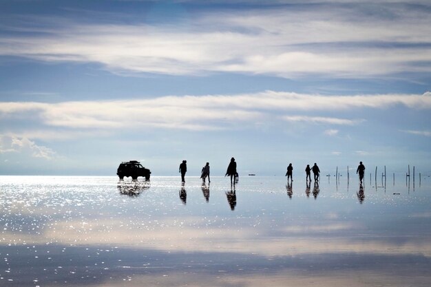 Foto pessoas a caminhar na praia com uma árvore ao fundo