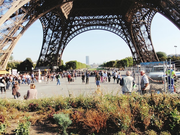 Foto pessoas a caminhar sob a torre eiffel