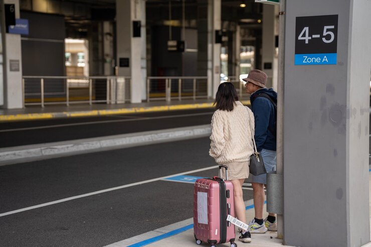 Foto pessoas à espera no aeroporto com malas a ver aviões a decolar