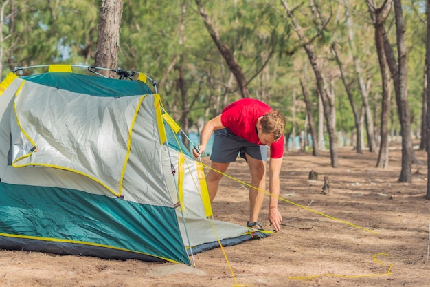 Pessoas acampando turistas de estilo de vida ao ar livre montando seu acampamento cinza verde na floresta de verão perto do mar de lazur Filho de menino bonito ajuda seu pai a montar barraca Educação natural das crianças