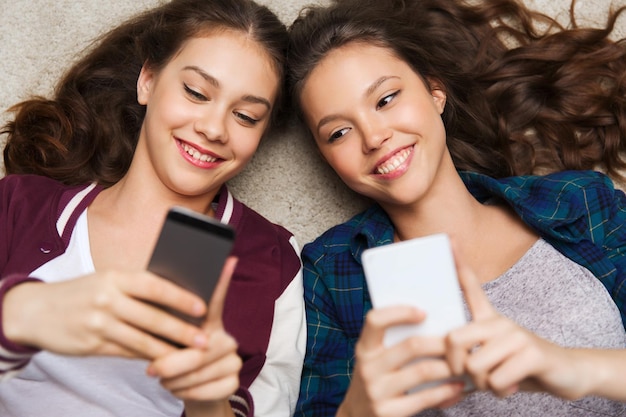 pessoas, amigos, adolescentes e conceito de amizade - felizes e sorridentes garotas adolescentes deitadas no chão com smartphones