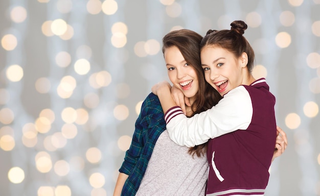 pessoas, amigos, adolescentes e conceito de amizade - felizes e sorridentes garotas adolescentes se abraçando sobre o fundo das luzes de férias