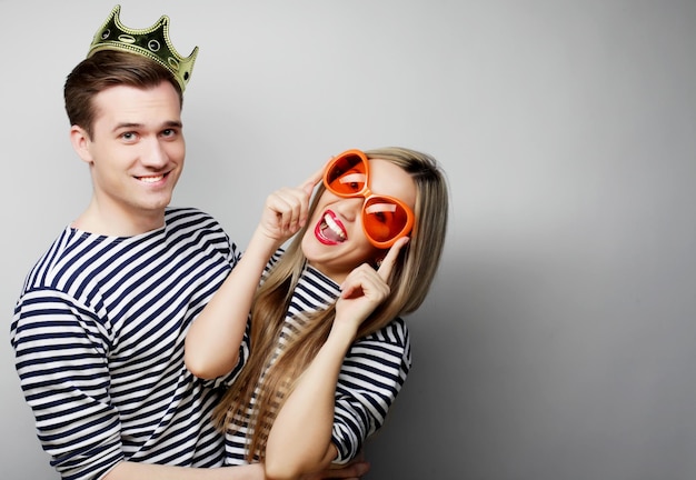 Pessoas amizade amor e lazer conceito belo jovem casal amoroso com microfone grandes óculos laranja e coroa pronto para a festa
