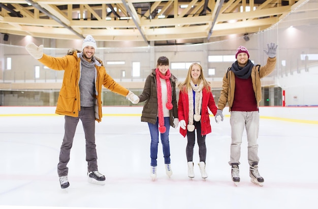 pessoas, amizade, gesto, esporte e conceito de lazer - amigos felizes acenando com as mãos na pista de patinação