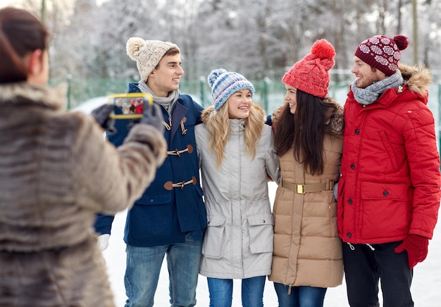 pessoas, amizade, inverno, tecnologia e conceito de lazer - amigos felizes tirando foto com smartphone ao ar livre