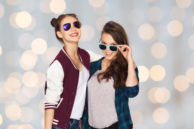 pessoas, amizade, moda, verão e conceito de adolescentes - felizes sorrindo lindas adolescentes em óculos de sol sobre fundo de luzes de férias