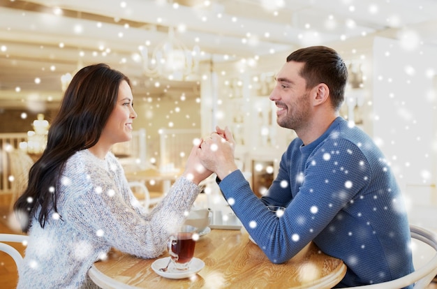 pessoas, amor, romance e conceito de namoro - casal feliz bebendo chá e de mãos dadas no café ou restaurante