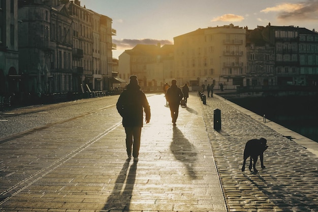 Pessoas andando na rua durante o pôr do sol na cidade de la Rochelle França