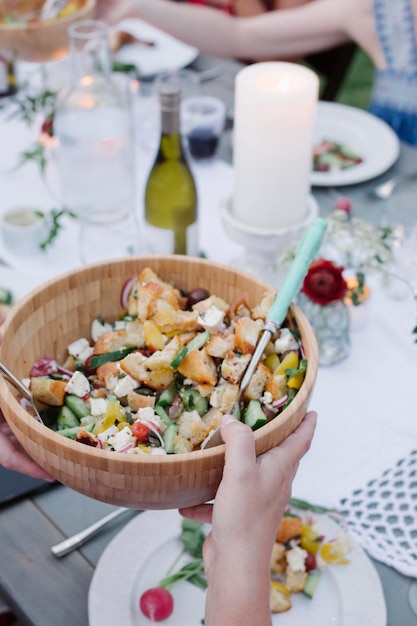 Pessoas ao redor de uma mesa em uma festa no jardim uma tigela de salada