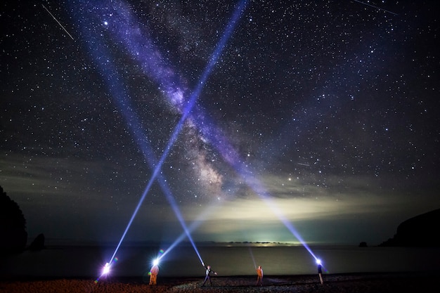 Foto pessoas brilham com lanternas de led a noite com a via láctea