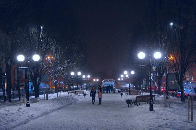 Pessoas caminham pela cidade durante a nevasca Nevasca à noite na cidade à noite com lanternas Calçada da cidade durante a neve Inverno de neve na cidade