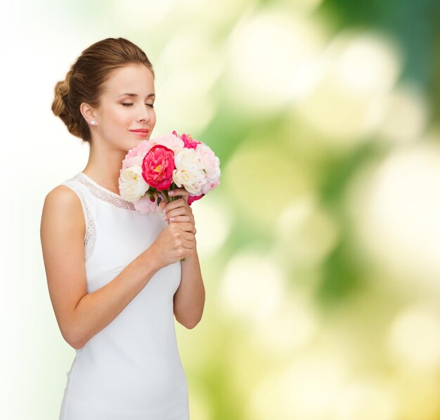 pessoas, casamento, feriados e conceito de celebração - sorrindo noiva ou dama de honra em vestido branco com buquê de flores sobre fundo verde