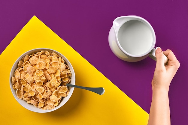 Pessoas com alimentação saudável e conceito de dieta fecham a mulher comendo muesli com leite no café da manhã sobre fundo roxo e amarelo