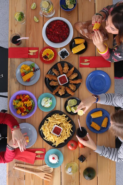 Pessoas com bebidas enquanto estão sentadas à mesa de jantar Comida na mesa Comida na mesa Pessoas comem fast food