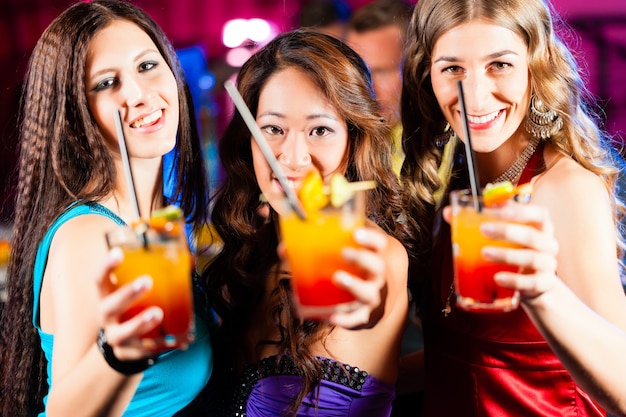 Pessoas com cocktails no bar ou clube