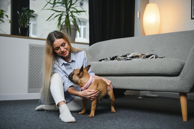 Pessoas com conceito de animais de estimação Mulher sorridente brincando no sofá com cachorro em casa