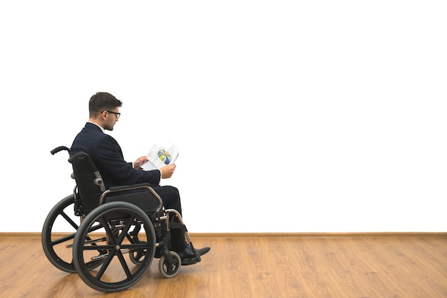 Pessoas com deficiência em uma cadeira de rodas segurando papéis no fundo branco da parede