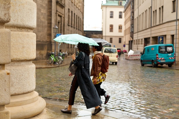 Pessoas com guarda-chuvas correm por uma cidade europeia na chuva