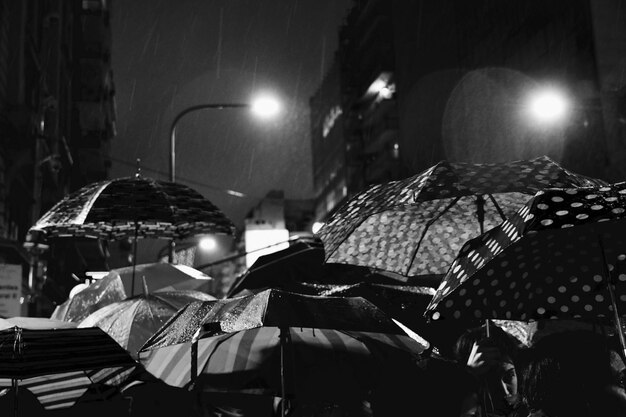 Foto pessoas com guarda-chuvas na rua à noite