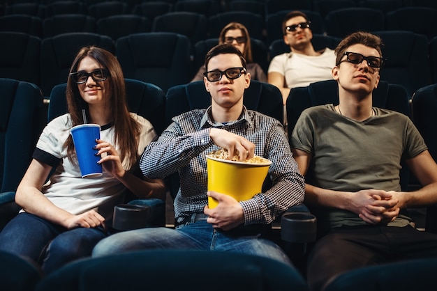 Pessoas com pipoca assistindo filme no cinema