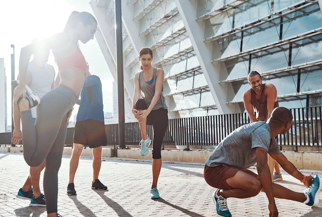 Pessoas com roupas esportivas se aquecendo e se alongando enquanto se exercitam na calçada ao ar livre