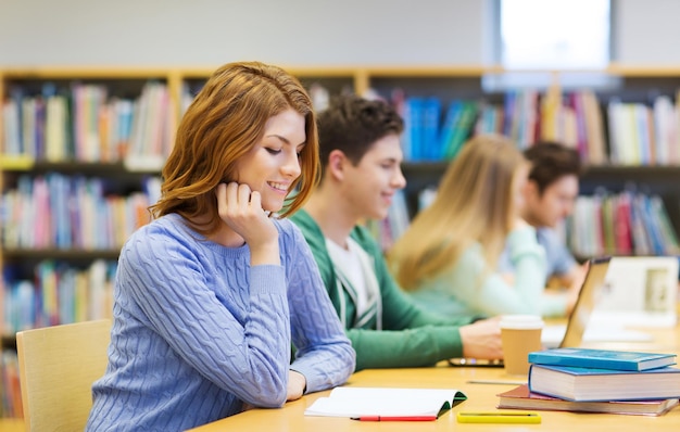 pessoas, conhecimento, educação e conceito escolar - estudante feliz lendo livros na biblioteca