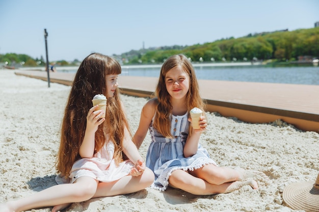 Pessoas crianças amigos e conceito de amizade garotinhas alegres comendo sorvete na praia