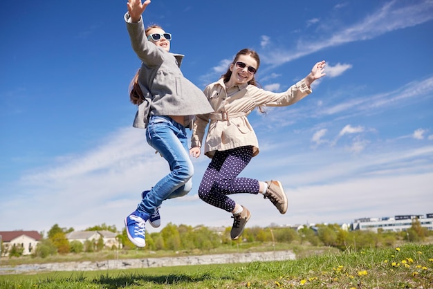 pessoas, crianças, amigos e conceito de amizade - meninas felizes pulando alto ao ar livre