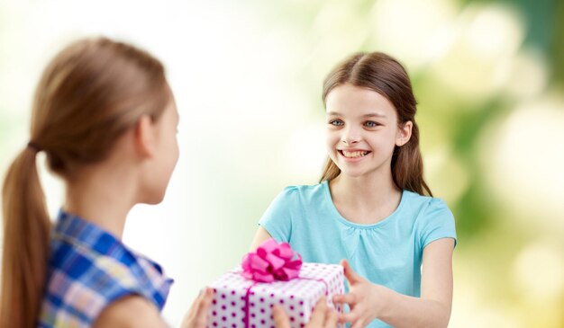 pessoas, crianças, feriados, amigos e conceito de amizade - meninas felizes com presente de aniversário sobre fundo verde